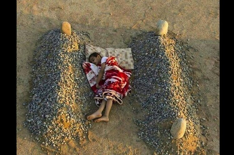 Сирийский мальчик спит между могил родителей