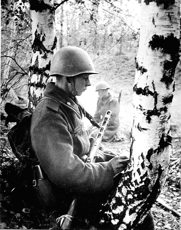 Молодой советский солдат пишет письмо домой в перерыве между боями. Рядовой вооружен пистолетом-пулеметом ППШ-41.