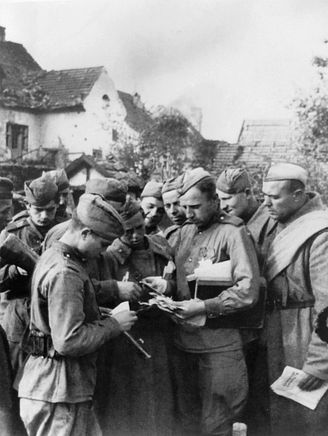 Советский солдат раздает письма сослуживцам.