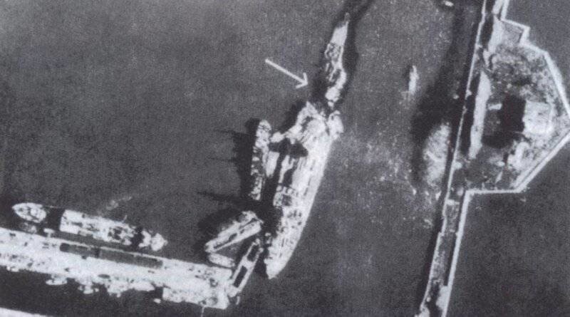 «Марат», стоящий у причала Усть-Рогатки в конце сентября 1941 г. Кадр немецкой аэрофотосъёмки. Стрелкой показано место взрыва. У борта стоит спасательное судно, из повреждённых цистерн ещё вытекает мазут