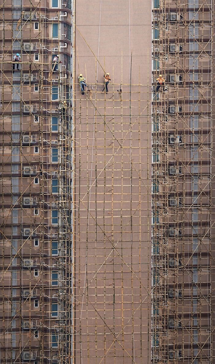2. "Бамбуковые ткачи". Рабочие устанавливает строительные леса из бамбука для ремонта фасада здания