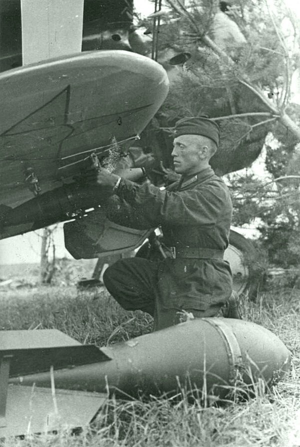 Сержант-техник Николай Крылов подвешивает реактивный снаряд под крыло истребителя И-153 «Чайка». Время съемки: июль 1941. 
