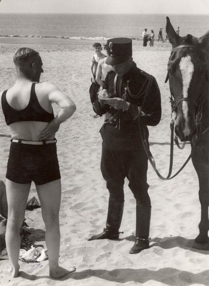 14. Человека на пляже Хемскерк в Нидерландах штрафуют за неподобающий внешний вид, 1931 год.