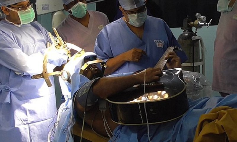 Пациент играет на гитаре во время операции на мозге