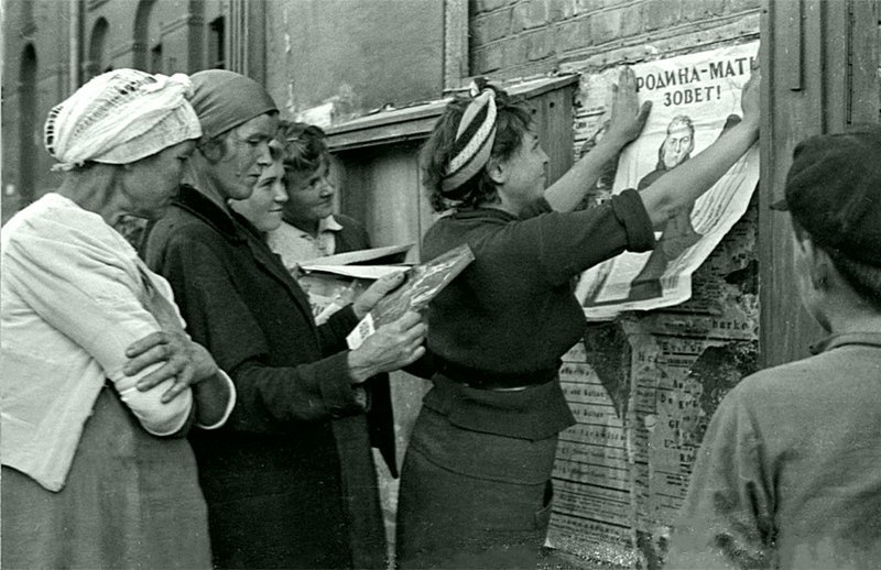 Женщина наклеивает на доску объявлений плакат «Родина-мать зовёт!». Знаменитый плакат времён Великой Отечественной войны был создан художником Ираклием Тоидзе в конце июня 1941 года. 