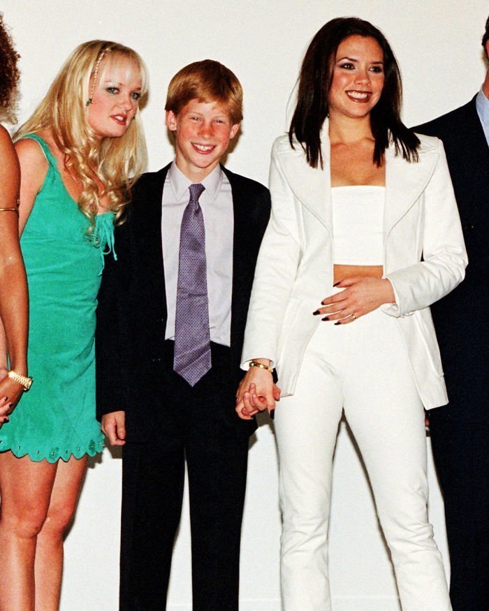 14. Принц Гарри держит за руку Викторию Бэкхем, фотографируясь с группой Spice Girls в 1997 году