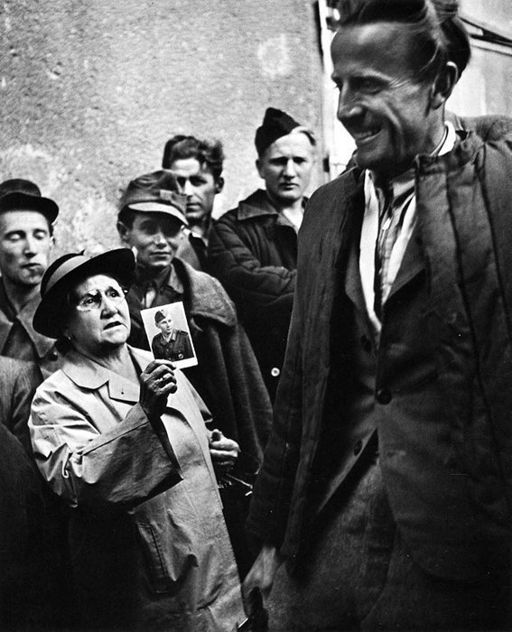 16. Мать показывает фотографию своего сына освобожденному заключенному после окончания Второй Мировой Войны