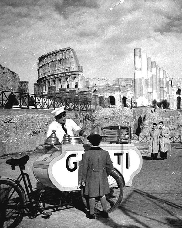 Ребенок покупает мороженое у продавца в Риме, недалеко от руин Колизея - 1940.