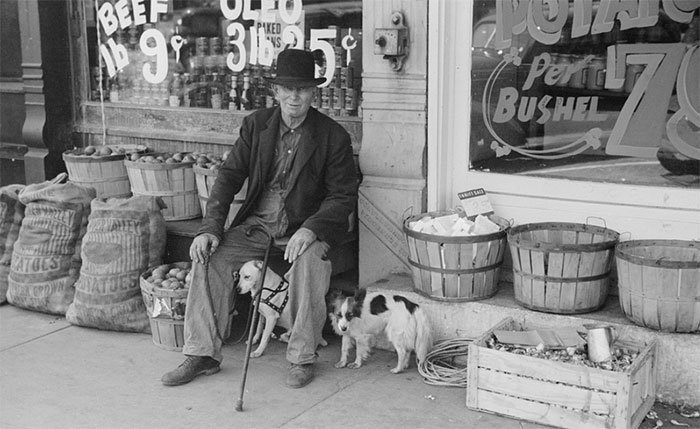Мужчина с собаками у продуктового магазина, Робинсон, штат Иллинойс, 1940 год 