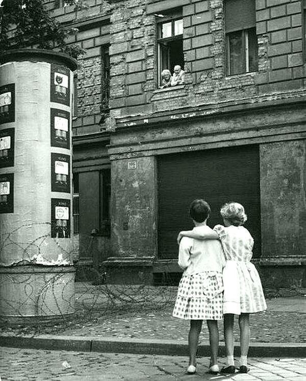 Две девочки разговаривают со своими бабушкой и дедушкой над колючей проволокой, которая позже стала Берлинской стеной. 1961