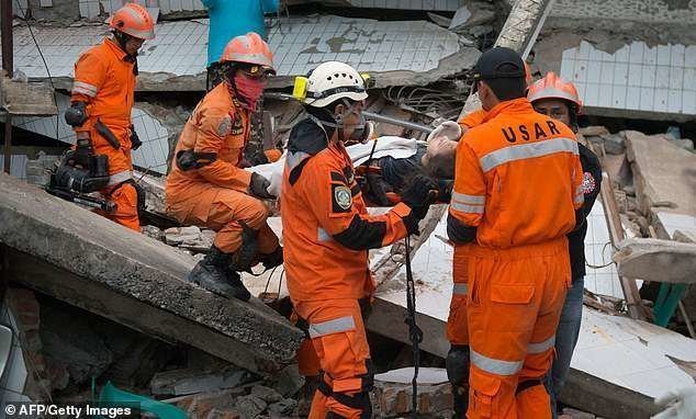 Спасатели эвакуируют женщину из разрушенного ресторана в Палу. Она выжила, но получила серьезные травмы
