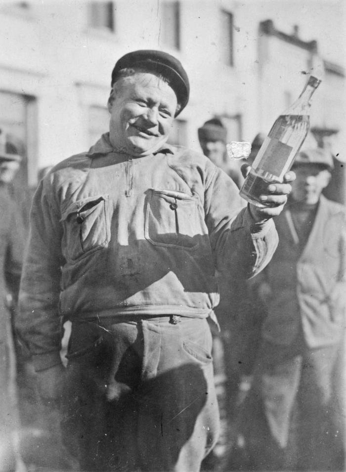 Финский кузнец Пирттимяки с бутылкой водки, которую он получил в подарок после того как отстоял в очереди всю ночь и стал первым покупателем магазина Alko после отмены сухого закона. Финляндская Республика. 5 апреля 1932 года.