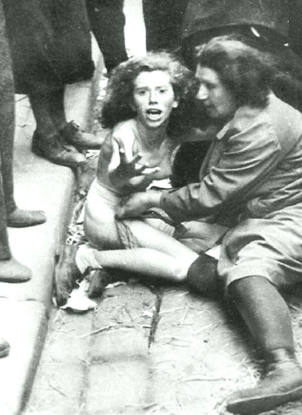 Обнаженная и униженная женщина кричит от ярости и тоски, когда пожилая женщина утешает ее, пока толпа окружает их во время еврейского погрома. Львов, 1 июля 1941 г. 