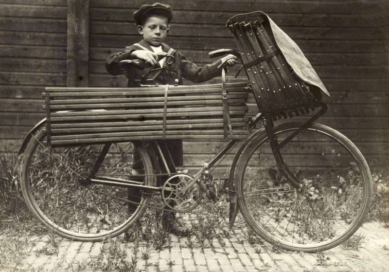 Мальчик перевозит складную лодку на своем велосипеде. 1916