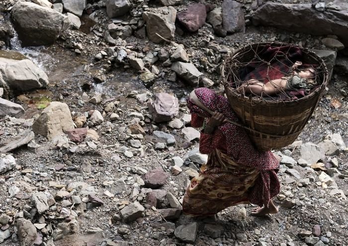 Женщина из племени кочевников Непала несет ребенка