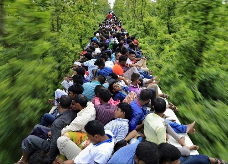  Люди едут на крыше переполненного поезда, чтобы успеть домой к религиозному празднику (Индия)