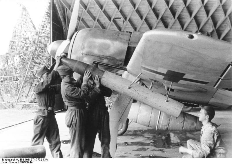 Аэродромные техники заряжают подкрыльевую ракетную установку Wfr. Gr. 21 калибра 210 мм на немецком истребителе Fw-190A