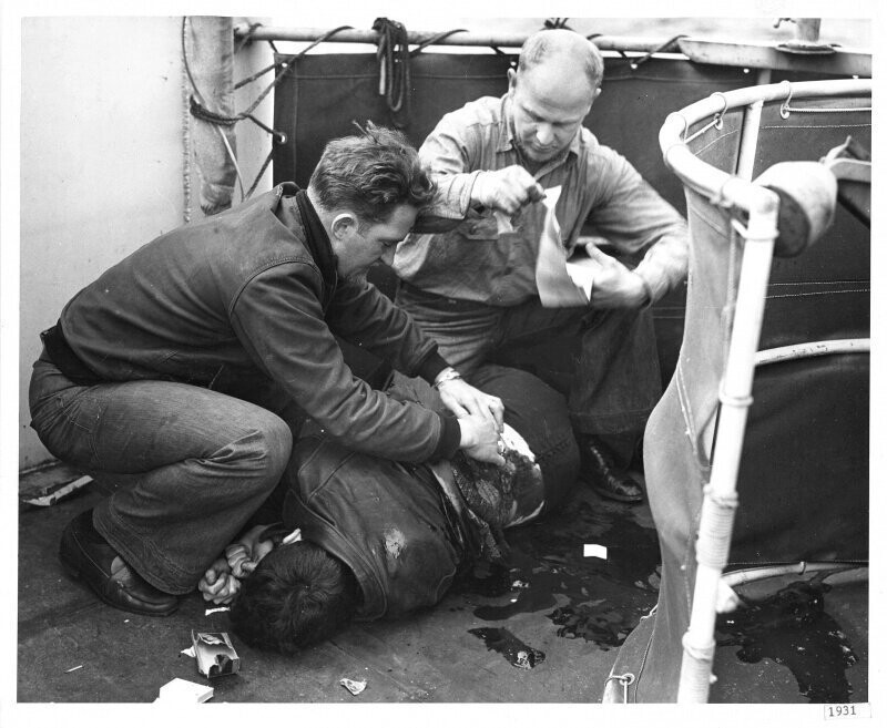 Оказание помощи смертельно раненному радисту 3-го класса Юлиусу Т. Петрелле на борту корабля береговой охраны "Спенсер". 17 апреля 1943 г.