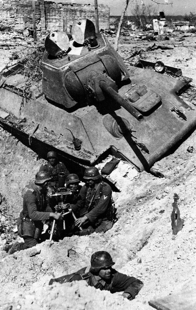 Немецкие миномётчики ведут бой в воронке от взрыва возле подбитого советского танка Т-34-76. Сталинград, октябрь 1942 г.