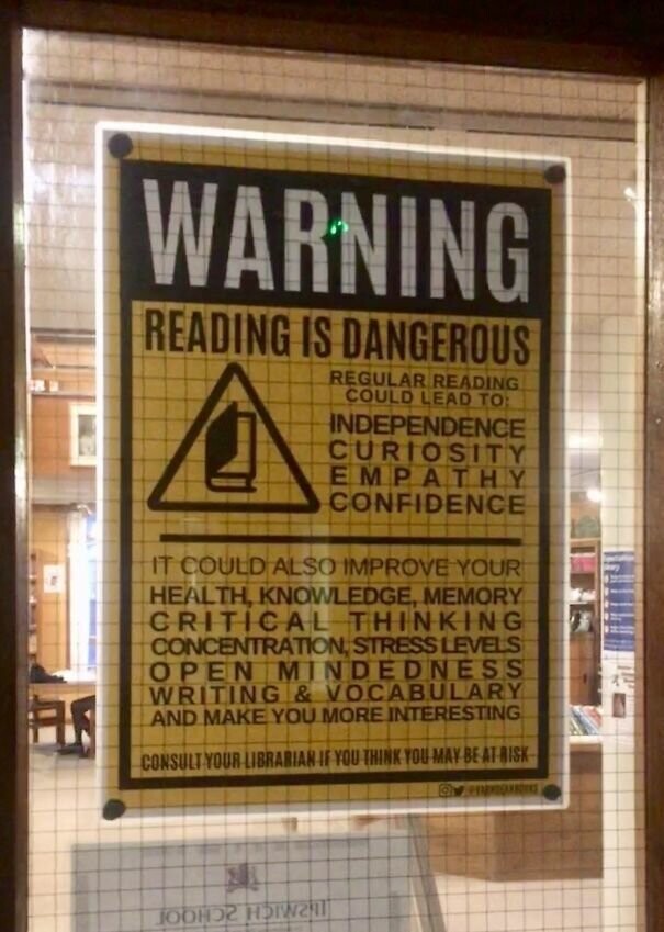 Знак рядом со школьной библиотекой, перечисляющий достоинства от чтения книг, как например, любознательность, независимость, эмпатия, уверенность, улучшение здоровья, памяти, знаний