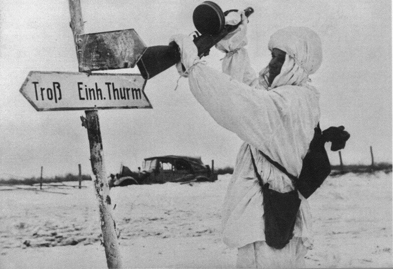 Советский солдат сбивает прикладом автомата немецкий дорожный указатель.