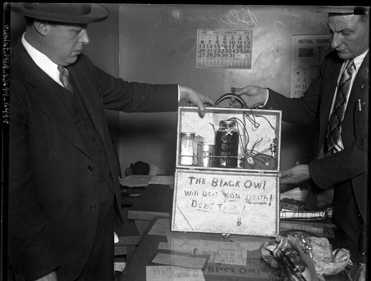 Два детектива демонстрируют чемоданчик со взрывчаткой, который использовался при попытке ограбления банка. 1932 год.