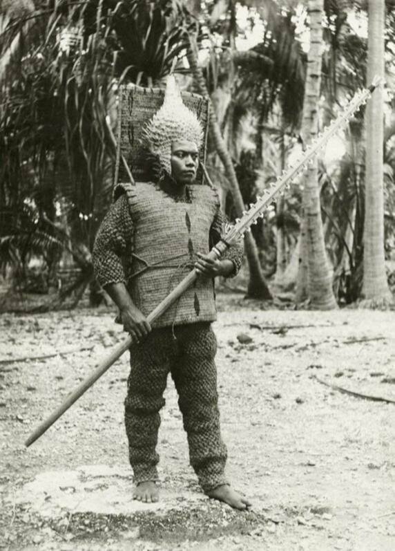 12. Воин Кирибати на острове Гилберта в 1900-м году в традиционном наряде: шлем рыбы-дикобраза, меч с акульим зубом и броня из кокосового волокна