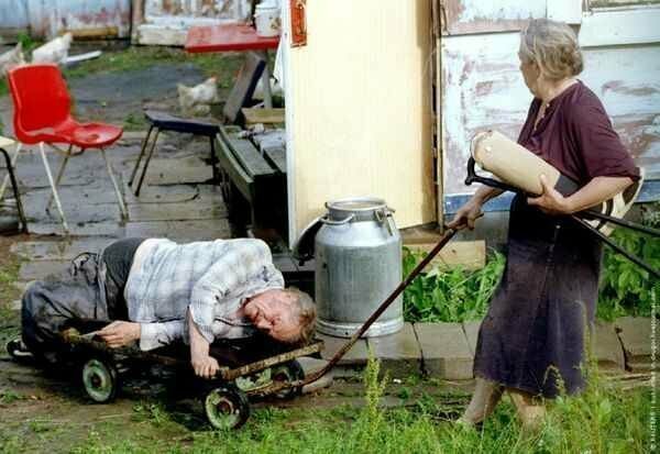 Жена везет на тележке пьяного мужа-инвалида. Деревня Семенково под Москвой, 1995 г.
