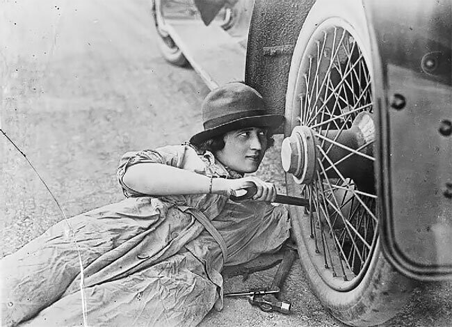 Женщина-водитель во время Первой мировой ремонтирует колесо