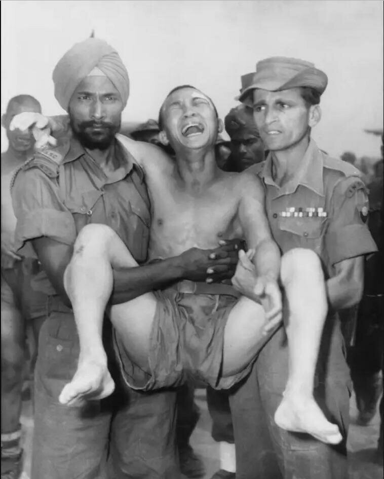Два индийских солдата несут плачущего китайского военнопленного в пункт обмена в Панмунжоме, Северная Корея, для возвращения коммунистам после войны в Корее в начале осени 1953 года. 