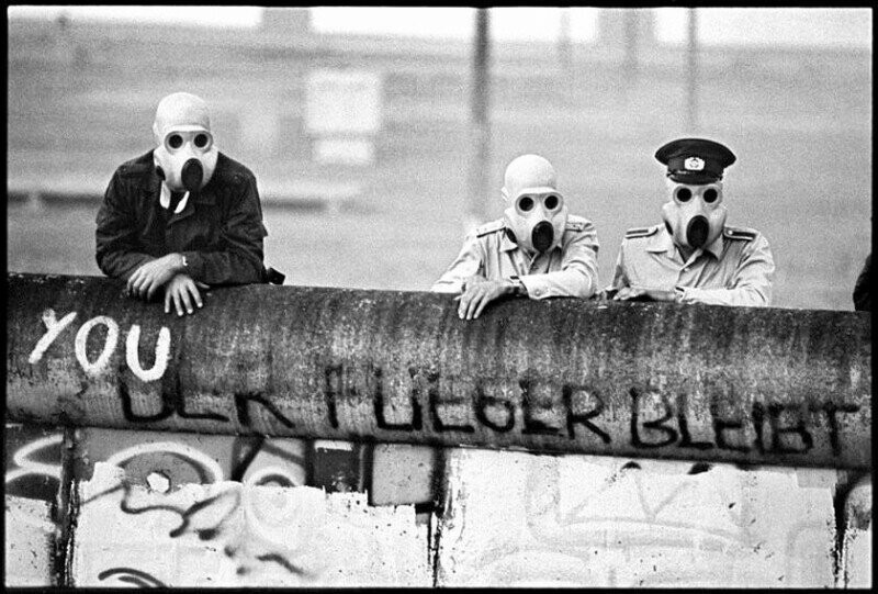 Восточногерманские пограничники наблюдают за разгоном демонстрантов с помощью слезоточивого газа по другую сторону берлинской стены, 1988 год.