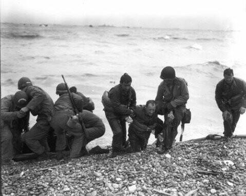 Американские солдаты уносят с берега раненых во время высадки