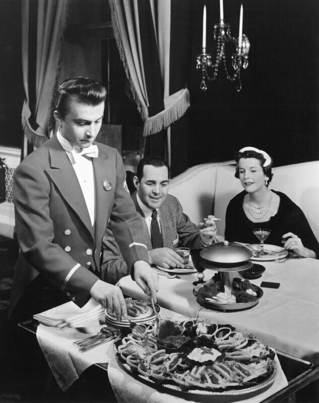 Официант подает мини хот-доги в отеле - Ambassador East Hotel в Чикаго, США. 12 апреля 1955 года.