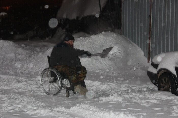 Мужчина в инвалидном кресле - коляске расчищал двор от снега и наледи, чтобы была возможность выехать, пройти и проехать