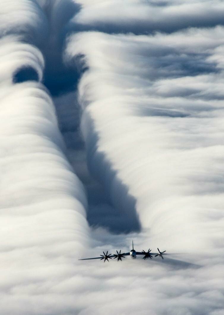 Многомоторный самолет разрезавший слои облаков своими пропеллерами