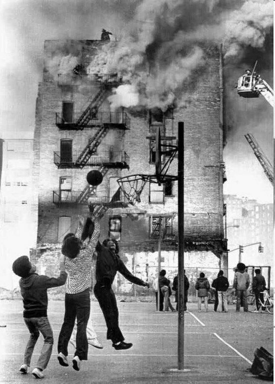 Дети играют в баскетбол на фоне горящего здания, Гарлем, Нью-Йорк, 1975 год.
