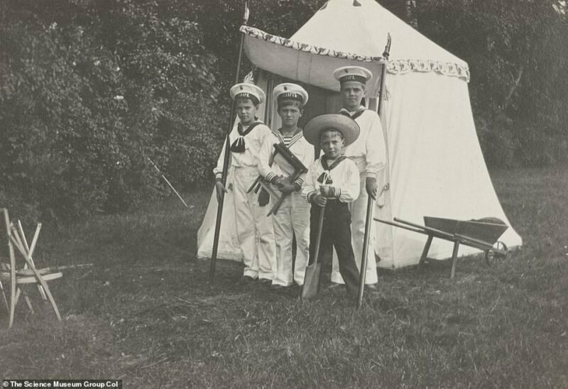 Четверо мальчиков, включая царевича Алексея Николаевича, в костюмах, напоминающих морскую форму, позируют на фоне шатра.