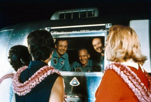 Астронавты Нил Армстронг, Базз Олдрин и Майкл Коллинз приветствуют своих жен из мобильного карантинного фургона на авианосце "Хорнет"