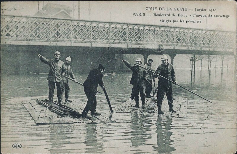 Пожарные плывут на вызов во время наводнения в Париже, январь 1910 года.