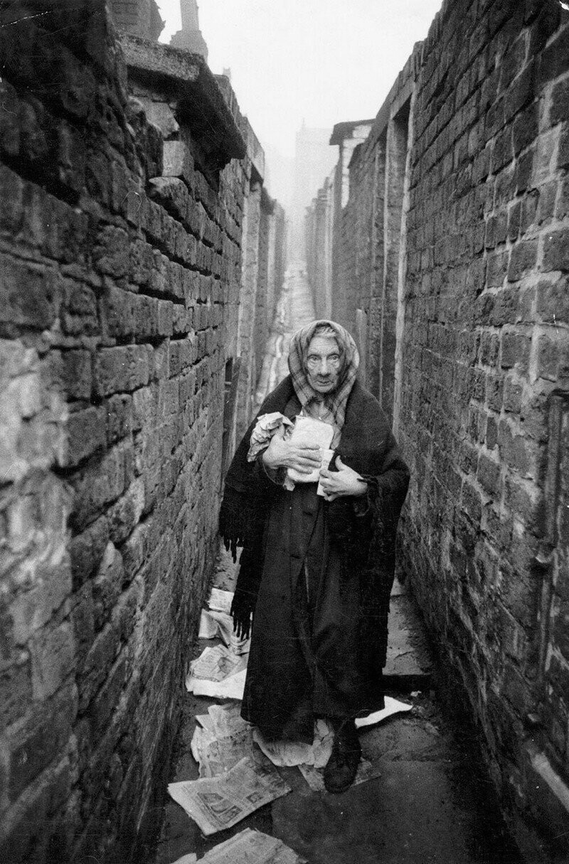 Пожилая женщина в переулке ливерпульских трущоб.