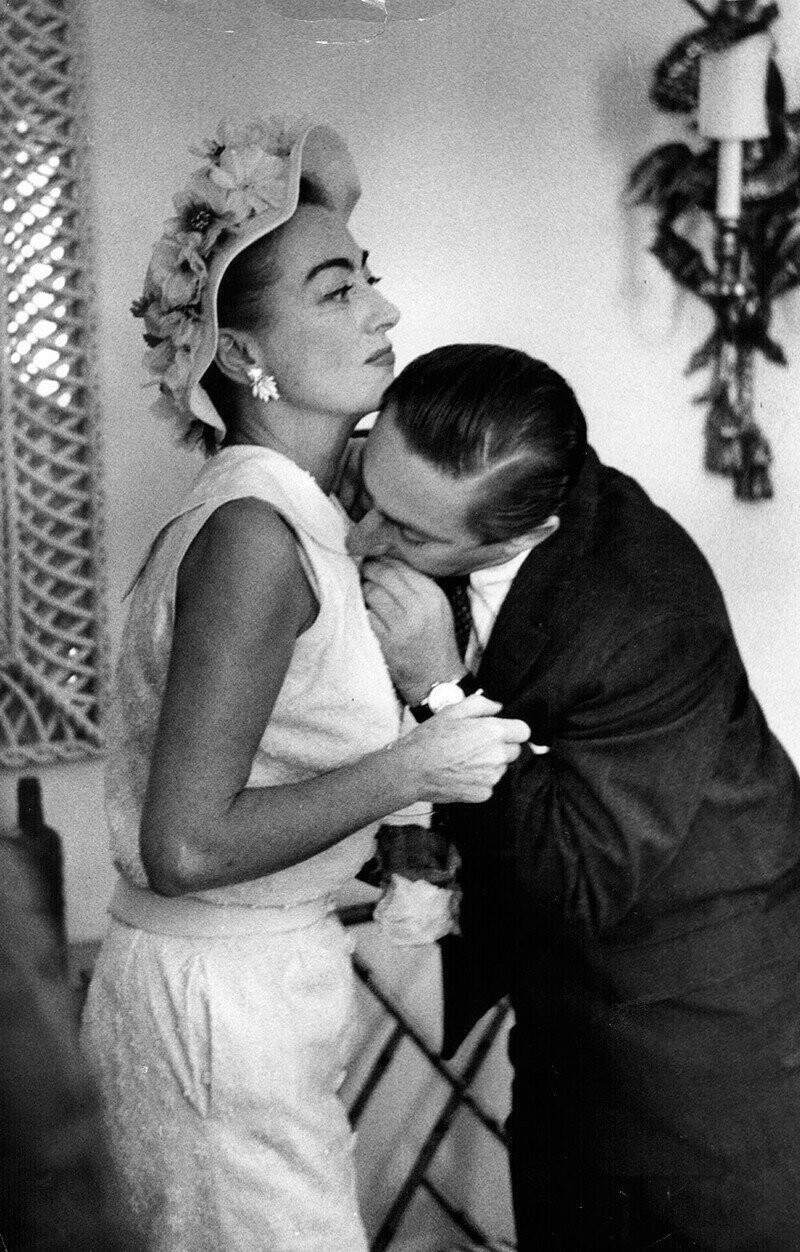 По просьбе американской актрисы Джоан Кроуфорд ассистент откусывает от её платья торчащую нитку в отеле «Дорчестер», Лондон, 1 июля 1956 года.