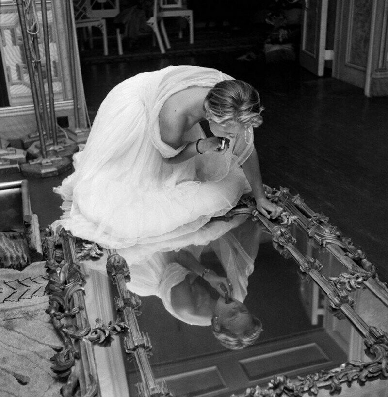 Участница конкурса красоты Джуди Данлоп в «Королевском павильоне» в Брайтоне наносит помаду в библиотеке. 8 августа 1953 года.