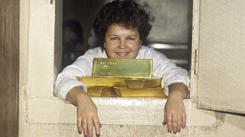 Достатка всем. Работница склада драгоценных металлов в Москве весело позирует со слитками золота, 1997 год