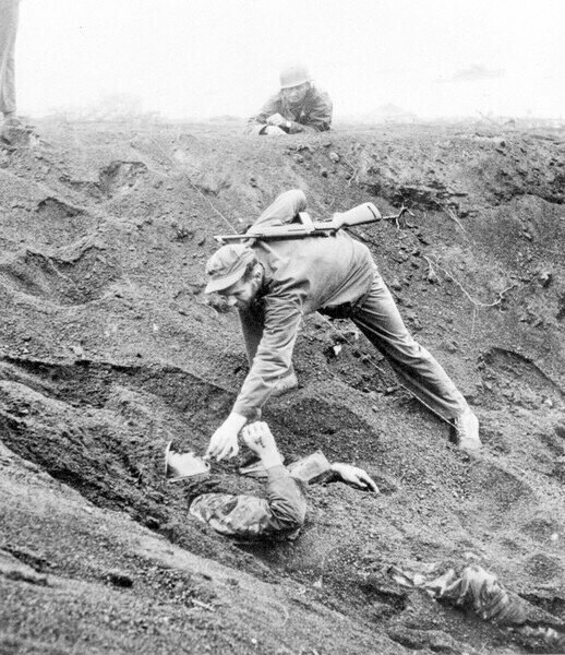 Кадр сделан в марте 1945 года в разгар битвы за Иводзиму - американский солдат дает покурить солдату Японии. Интересно, что японец  1,5 дня лежал с гранатой, поджидая американцев, но промахнулся. Сигарету ему дали в обмен на отказ сопротивления