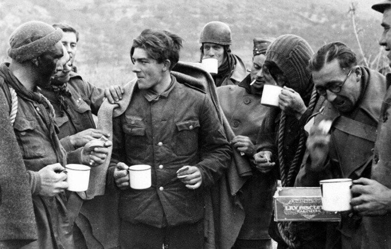 Британские коммандос делят чай и печенье с немецким пленным, которого они захватили во время рейда, 1944.