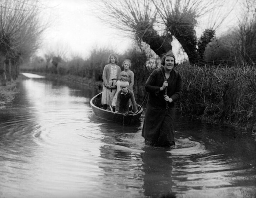 Мать везёт своих детей в школу во время наводнения в городе Бриджуотер. Англия, 1935 год.