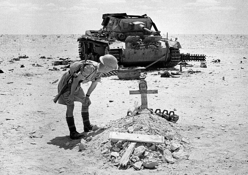 Солдат британской армии смотрит на крест над могилой погибшего немецкого танкиста