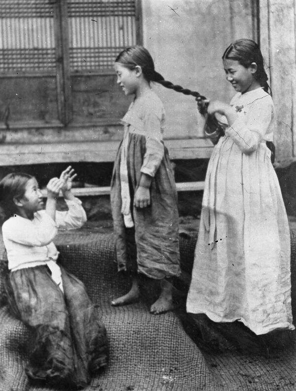 Три девочки играют на порожках здания.