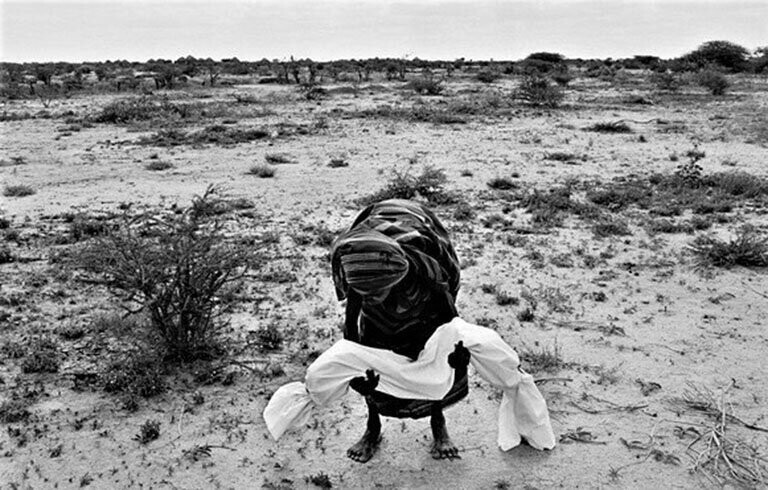 Мать поднимает тело своего ребенка, который умер от голода, чтобы отнести его в могилу. Бардера, Сомали, Ноябрь 1992 года. 
