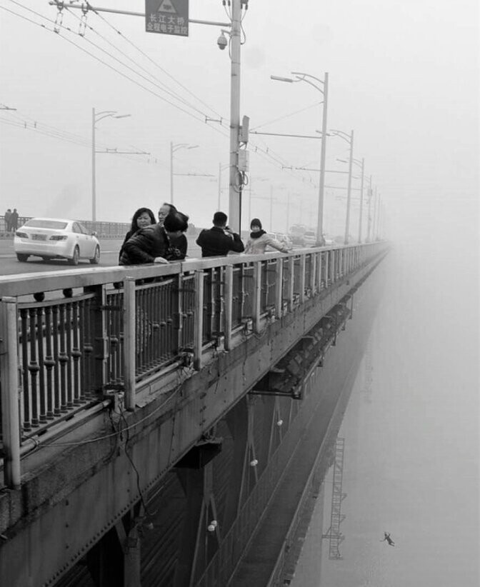 Китайский репортер, который пытался запечатлеть туман на реке Ухань Янцзы, лишь после детального изучения фото обнаружил, что на снимке запечатлен мужчина в момент падения с моста, как выяснилось позже, через несколько секунд за ним прыгнула его деву